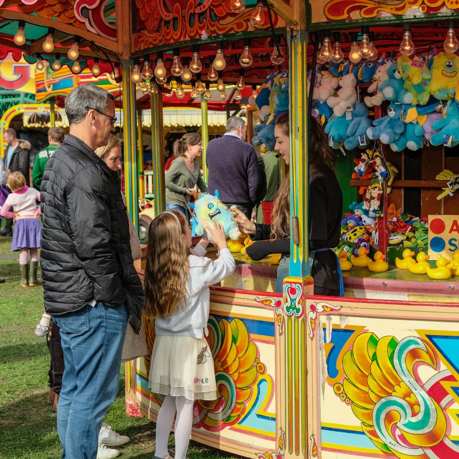 A child winning a soft toy prize at the hook a duck fairground game